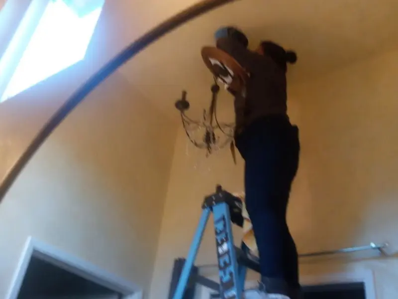 Electrician installing a chandelier in a Bakersfield residence
